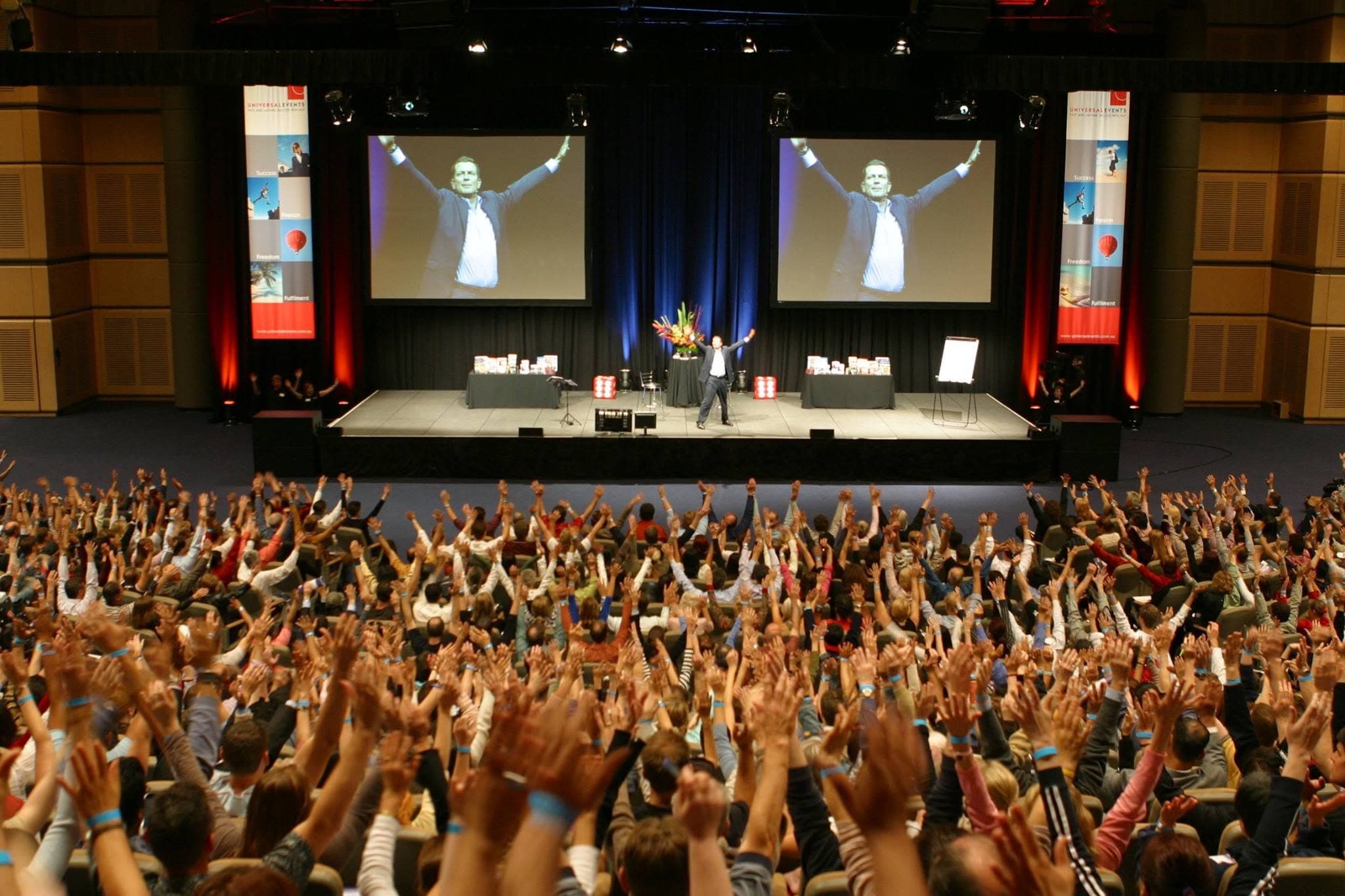 A full auditorium with every hand raised, Chris Howard on stage between two screens